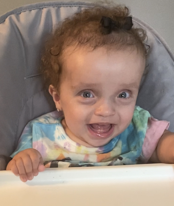 hailey smiling in high chair