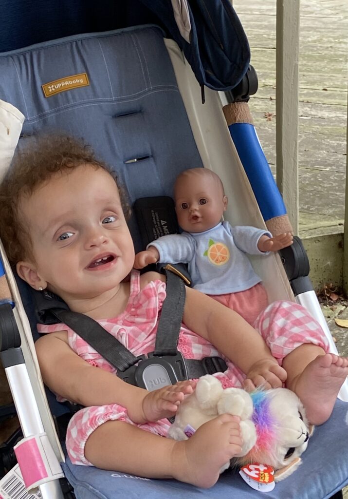 Hailey sitting in stroller doll to her right